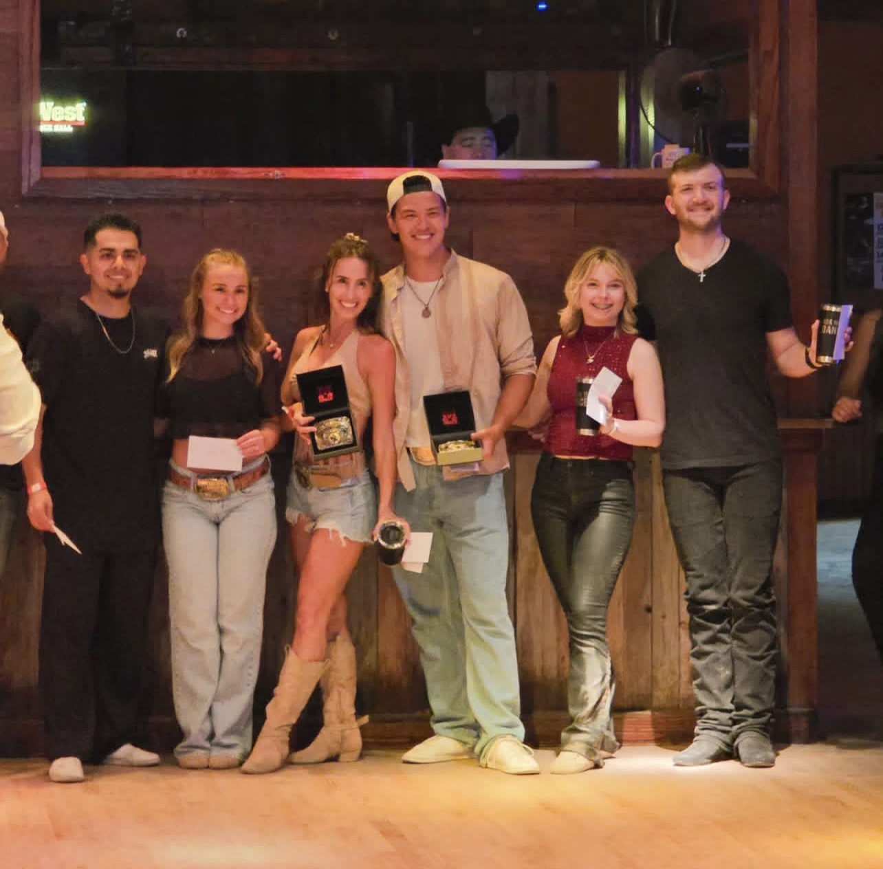 Nolan with fellow competitors holding their prize belt buckles after a country-western dance competition