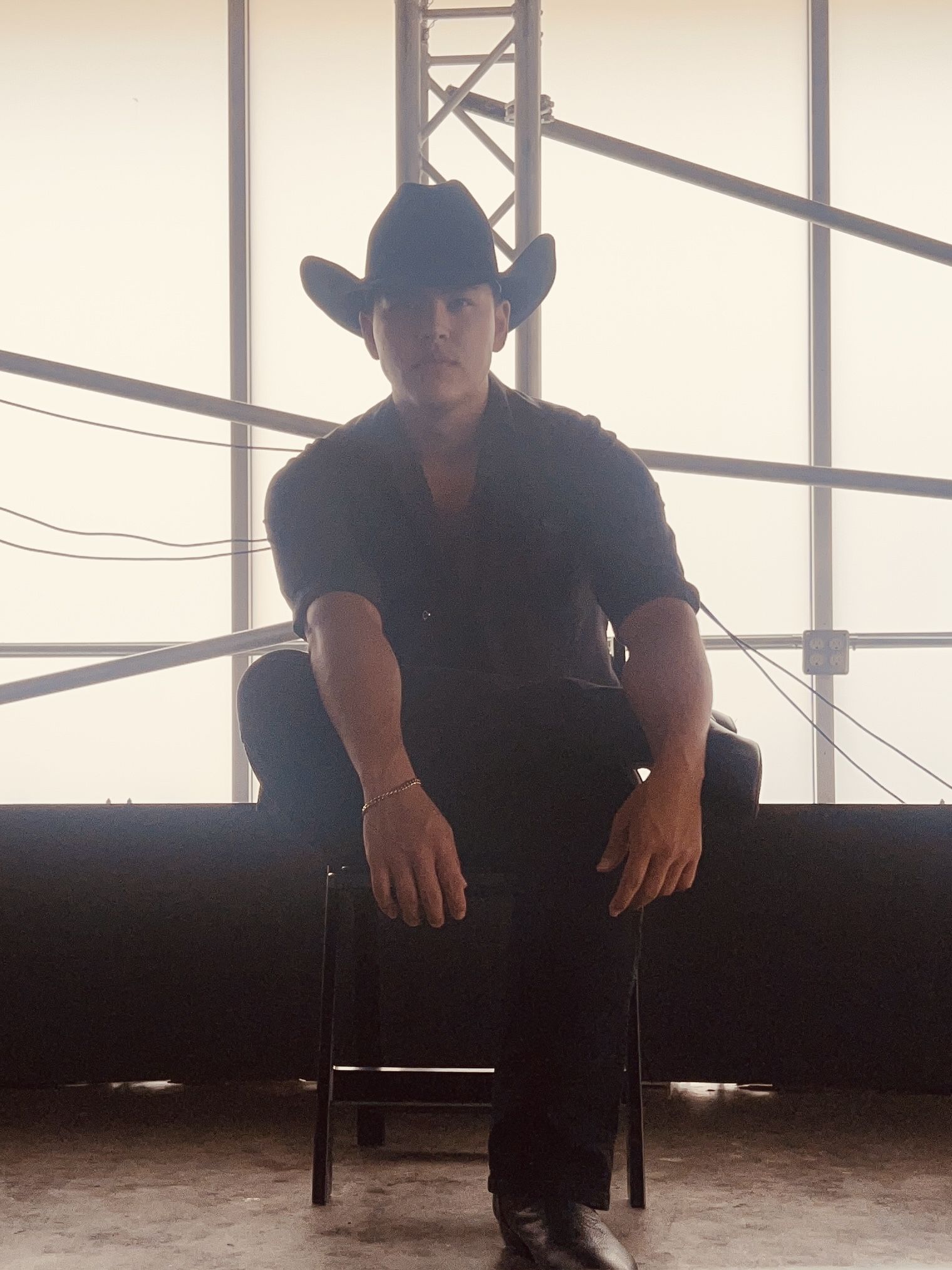 Nolan Wayne in a black cowboy hat, sitting in a bright studio